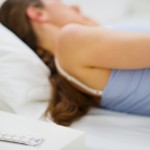 Closeup on pills and glass of water on table and sleeping girl in background